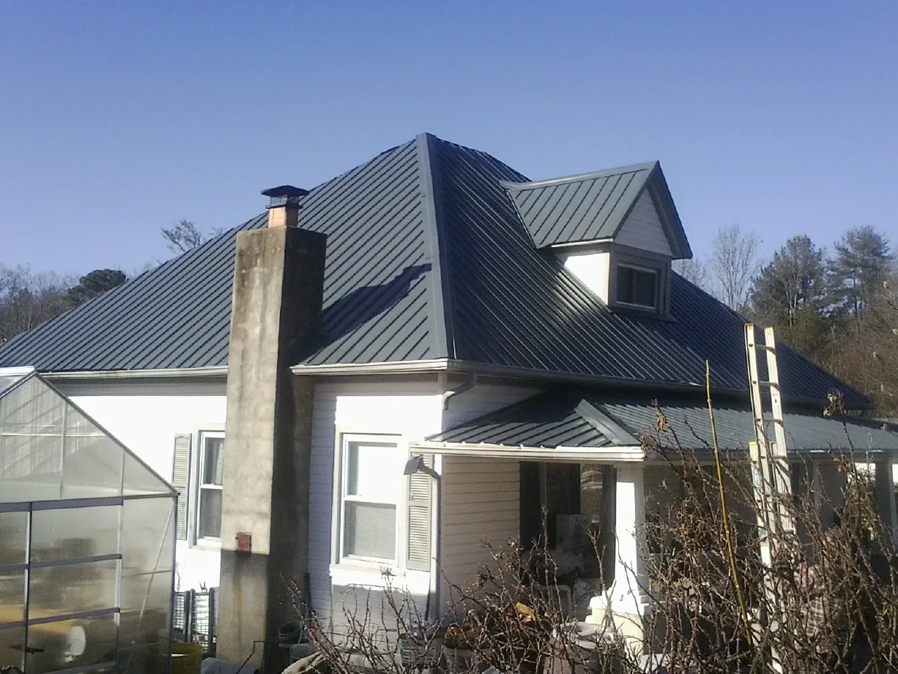 Dark blue standing seam metal roof on a white farmhouse with dormer — Slate & Tile Roof Repair by Roofing Brothers in Kennett Square