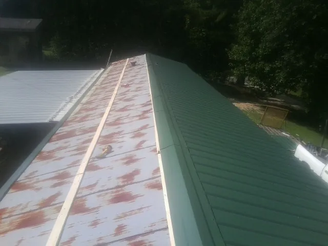Old rusted panels beside newly installed green metal roofing — Wind Damage Roof Repair by Roofing Brothers in Kennett Square