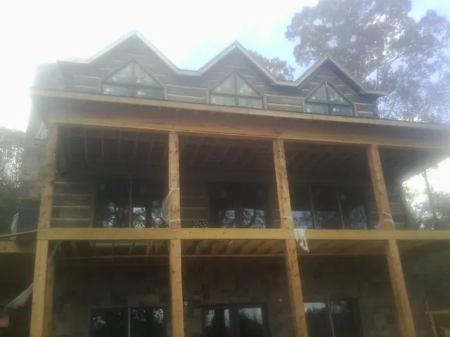 Dormers and porch framing on a large log home under construction — Roof Coating work by our crew in Kennett Square