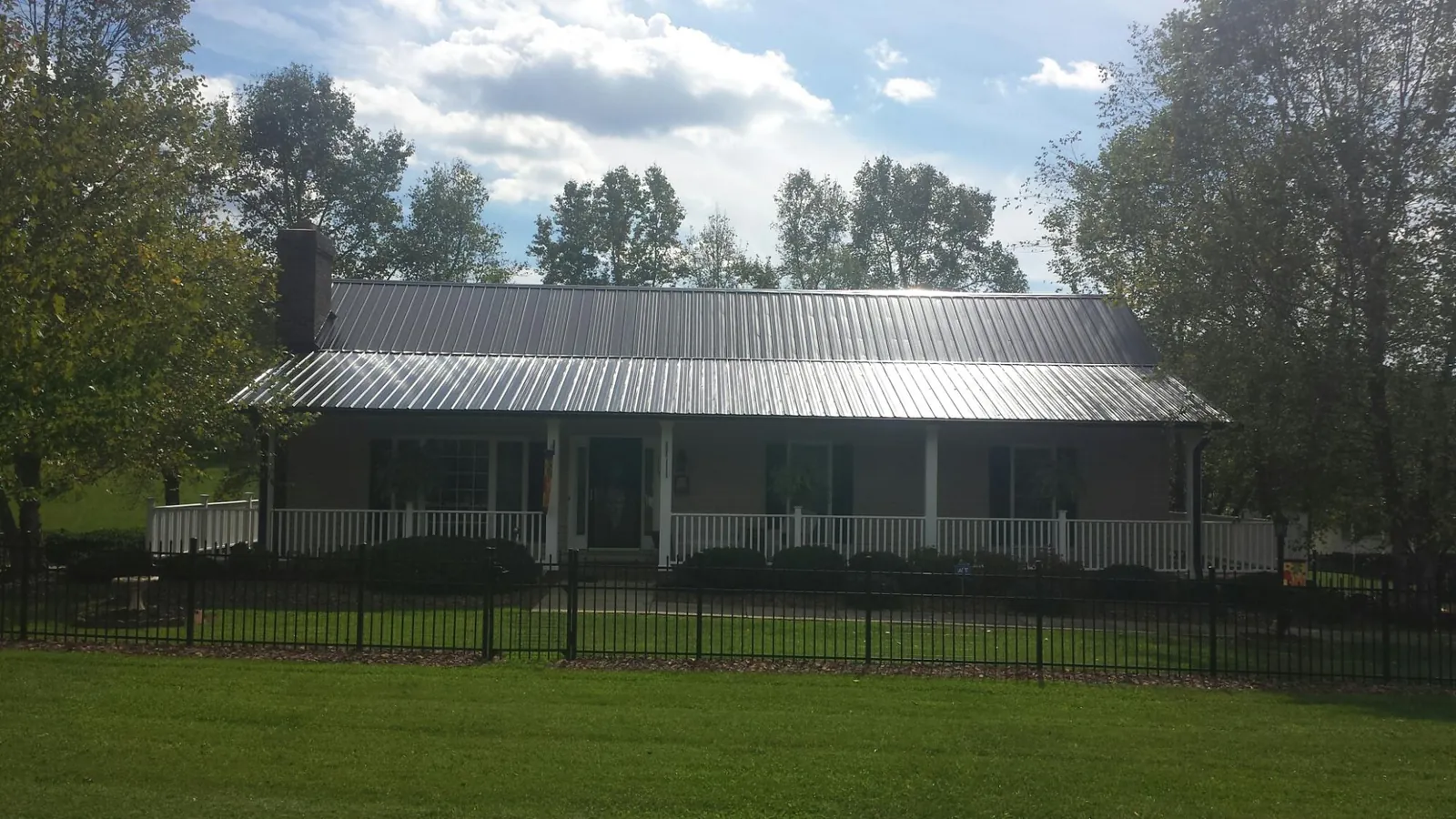 Gray metal roof on a brick ranch with a full width front porch — Gutter Guard Installation work by our crew in Kennett Square
