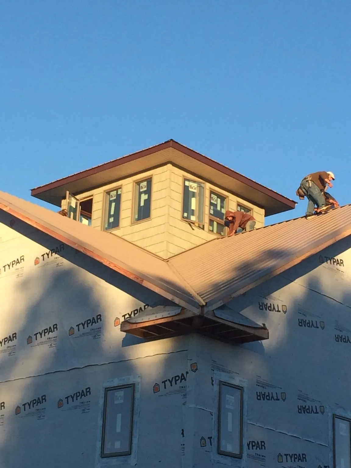 Roofers working around a rooftop cupola on a new metal roof at sunset — Roof Waterproofing in Kennett Square by Roofing Brothers